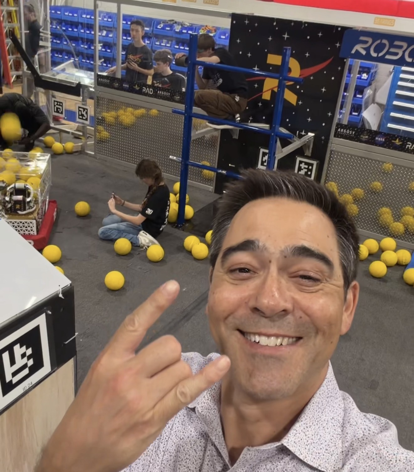 Owen Conflenti inside the Robonauts (Team 118) facility in Clear Creek ISD, with students working on the competition robot in the background
